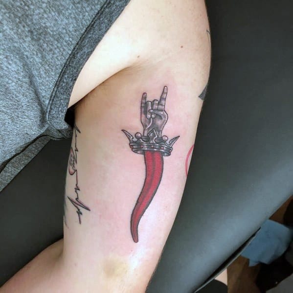 Red Italian horn tattoo with a crowned mano cornuto hand, symbolizing luck, protection, and a rock-inspired edge.