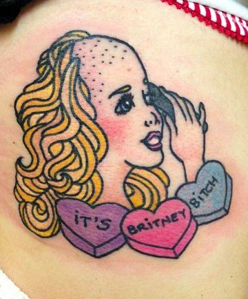 A colorful tattoo of a stylized Britney Spears with a partially shaved head, surrounded by candy hearts reading 'It's Britney, B****' in bold lettering.