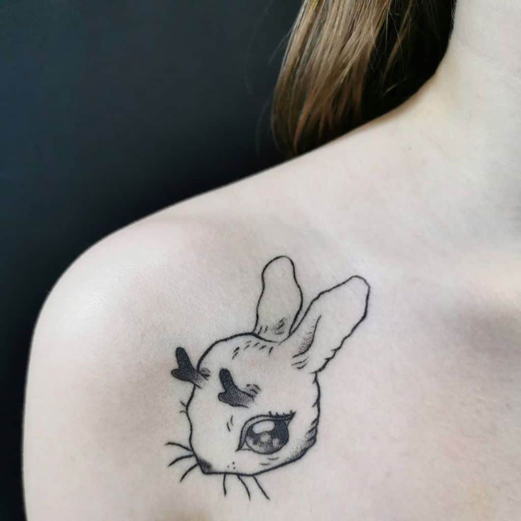 Minimalistic tattoo of a rabbit's face with delicate antlers and large expressive eyes, drawn with fine black lines