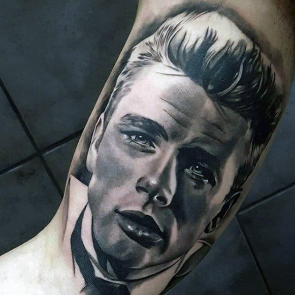 Hyper-realistic tattoo of James Dean's face with sharp contrast, slicked-back hair, and intense expression, placed on the inner arm.