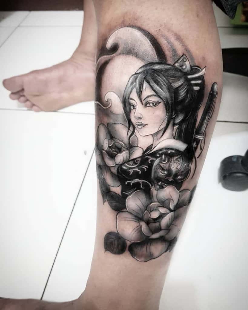 Black and gray tattoo of a warrior Geisha with a katana, surrounded by flowers, a moonlit background, and a fierce mask on her chest.