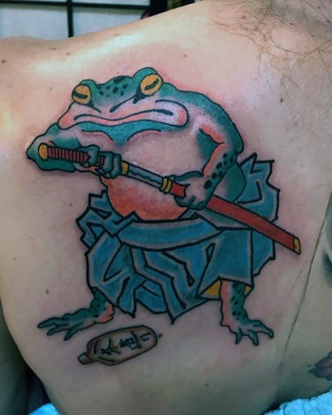Japanese-style back tattoo featuring a warrior frog dressed in samurai robes, gripping a katana, with a sake bottle nearby, symbolizing strength and discipline.