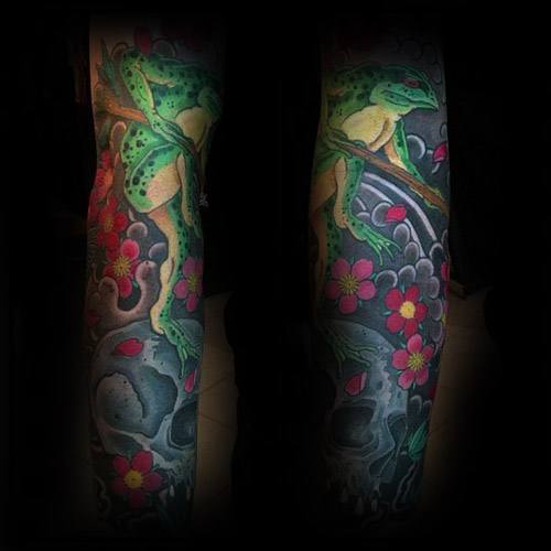 Japanese-style full-sleeve tattoo featuring a green frog on a branch, surrounded by pink cherry blossoms, swirling waves, and a detailed skull.