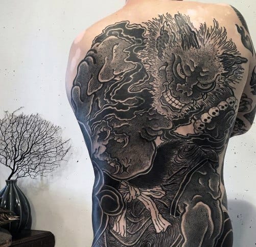 Full back Japanese-style tattoo of a fierce mythological creature with dynamic clouds and beads, symbolizing strength, chaos, and spiritual power.