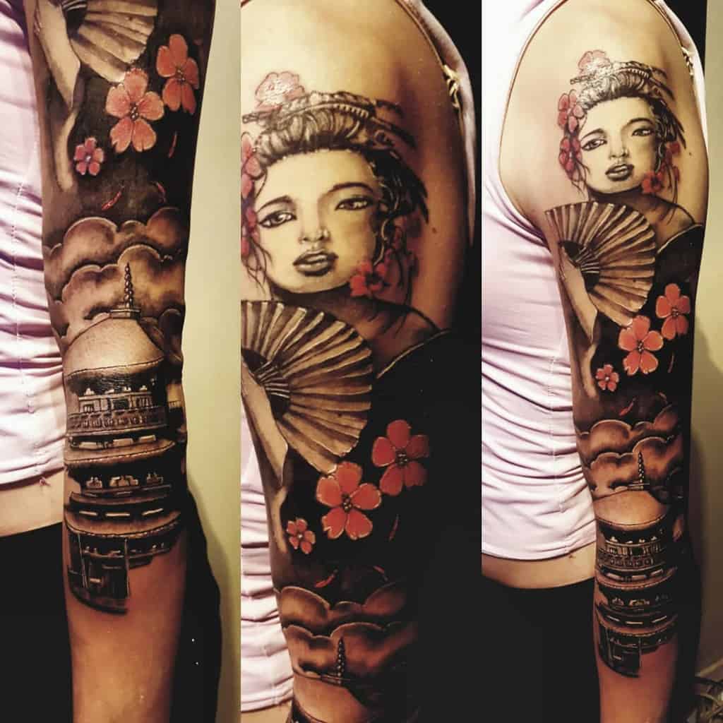 Full-sleeve tattoo of a Geisha holding a fan, with red cherry blossoms, a traditional pagoda, and soft cloud shading in a Japanese-inspired style.
