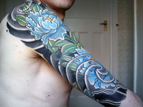 Man with a colorful floral sleeve Japanese tattoo on his upper arm and shoulder