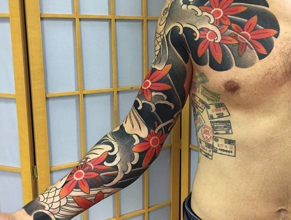 Japanese Irezumi-style tattoo sleeve featuring bold red flowers, black and grey wave patterns, and intricate shading for a traditional look.