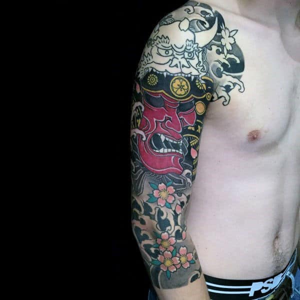 Japanese-style half-sleeve tattoo featuring a fierce red Hannya mask, intricate floral patterns, cherry blossoms, and bold black shading