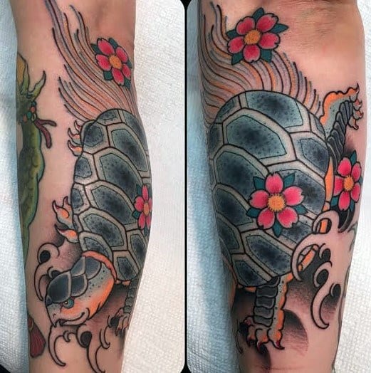 Japanese-style turtle tattoo on the leg with flowing lines, cherry blossoms, and bold shading, symbolizing longevity and resilience.
