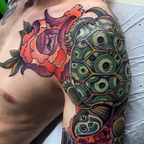 Japanese-style shoulder and arm tattoo featuring a detailed green turtle, vibrant peonies, and bold shading, symbolizing wisdom and longevity.