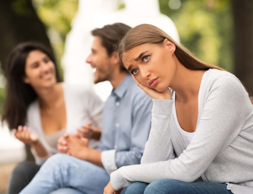jealous woman sitting next to his boyfriend while talking to his friend