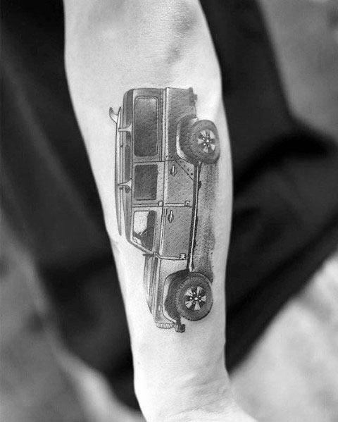 Realistic black and grey tattoo of a Jeep Wrangler in side view, placed on the forearm with detailed shading and depth.