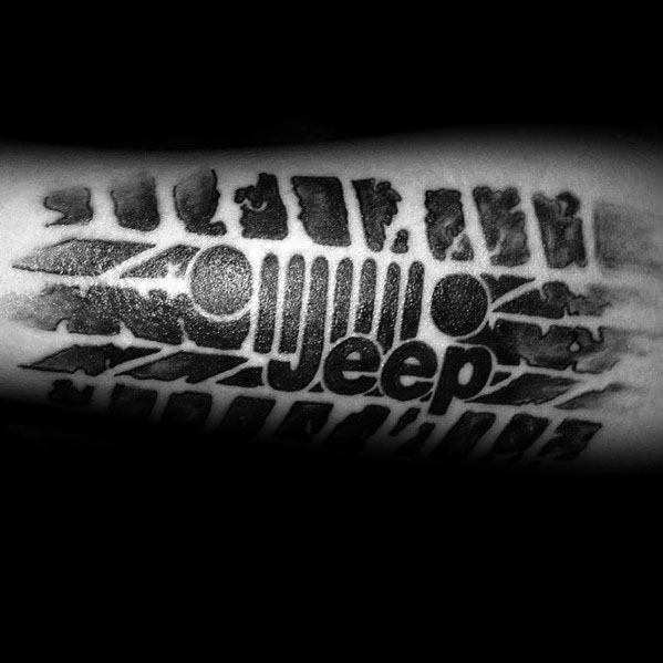 Bold black and grey tattoo featuring a Jeep grille logo integrated into a rugged tire tread design, symbolizing off-road adventure.