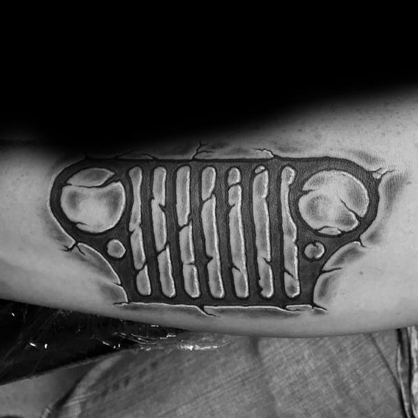 Black and grey tattoo of a Jeep grille with a ripped skin effect, creating a 3D illusion of the design emerging from beneath the skin.