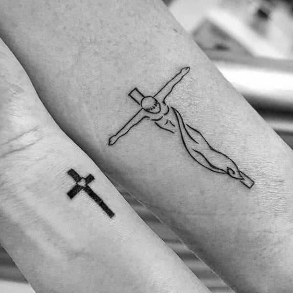 Two forearms with tattoos: a small cross on one arm and a crucifix on the other