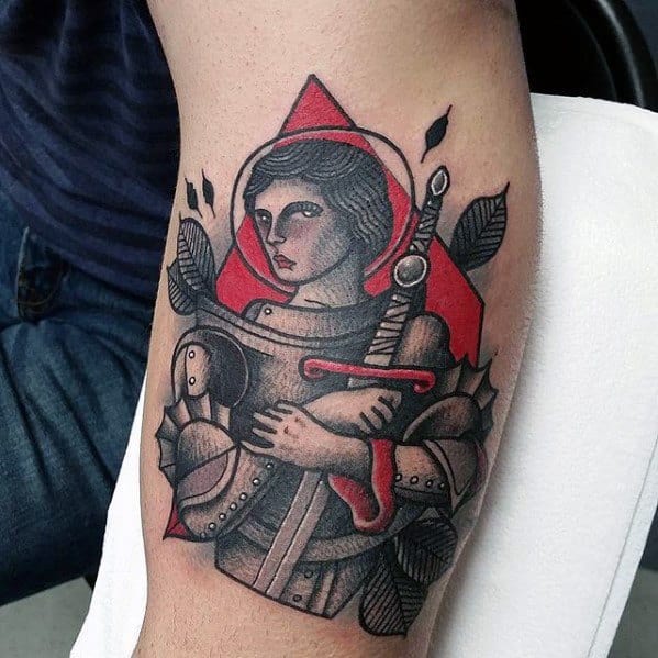 Bold Joan of Arc tattoo with red hood, stylized armor, and sword, combining traditional and illustrative elements with sharp contrasts.