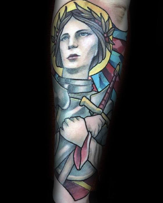 Colorful forearm tattoo of Joan of Arc with a soft, painterly style, featuring a sword, halo, and stained glass-inspired background.
