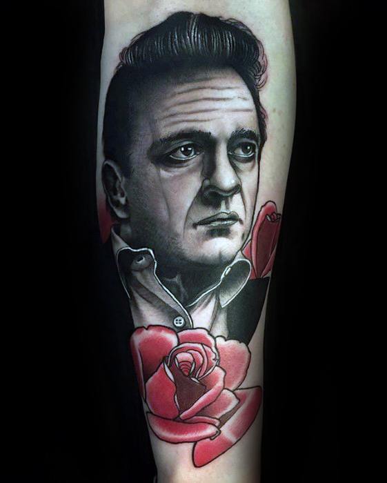 Tattoo of Johnny Cash with rose designs in black, white, and red on forearm