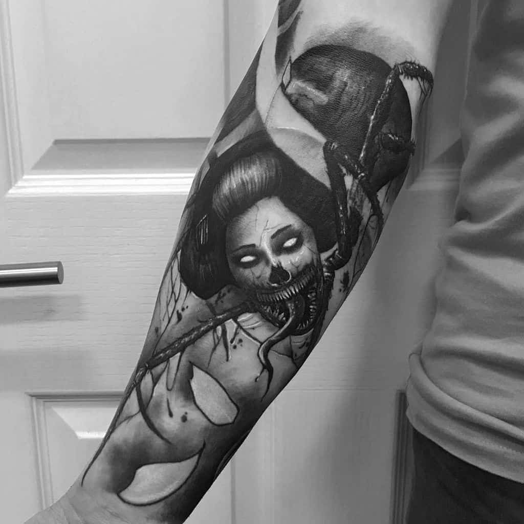 Dark and surreal black and gray tattoo of a Geisha with glowing eyes, skeletal mouth, and a large spider crawling on her head and body.