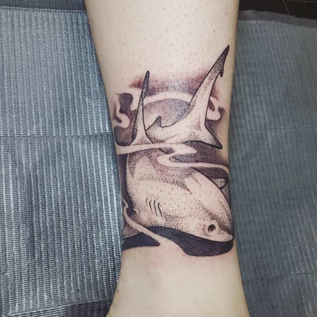 Ocean-themed tattoo featuring a detailed hammerhead shark with bold shading and flowing water elements