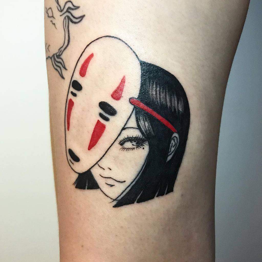 Stylized tattoo of Tomie from Junji Ito wearing No-Face’s mask from Spirited Away, blending bold black ink, red accents, and delicate facial details