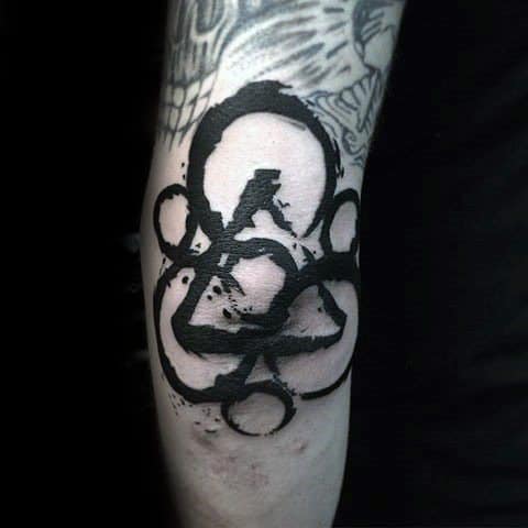 Bold black Keywork tattoo on the forearm with heavy brushstroke texture, showcasing Coheed and Cambria’s emblem in a raw, expressive style.