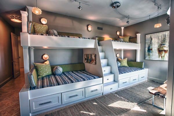 Modern bedroom with double bunk beds, striped bedding, green cushions, warm lighting, and bunk-friendly artwork