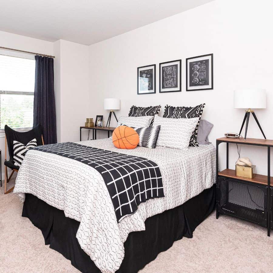 Black and white bedroom with sports-themed decor, basketball on bed, and framed art.
