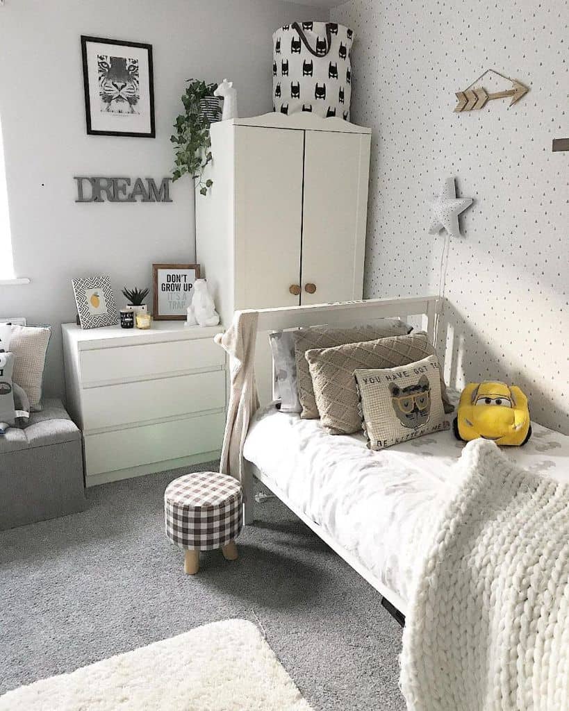 Cozy children's room with a bed, white dresser, and cute decor, including a toy car and framed art