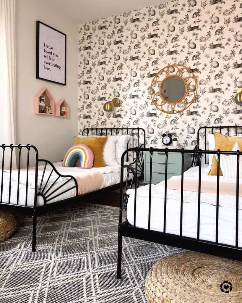 Cozy bedroom with two black metal beds, floral wallpaper, decorative mirror, and colorful accent pillows