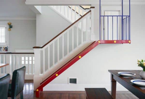 A bright room features a dining table, with an indoor slide elegantly running alongside the staircase