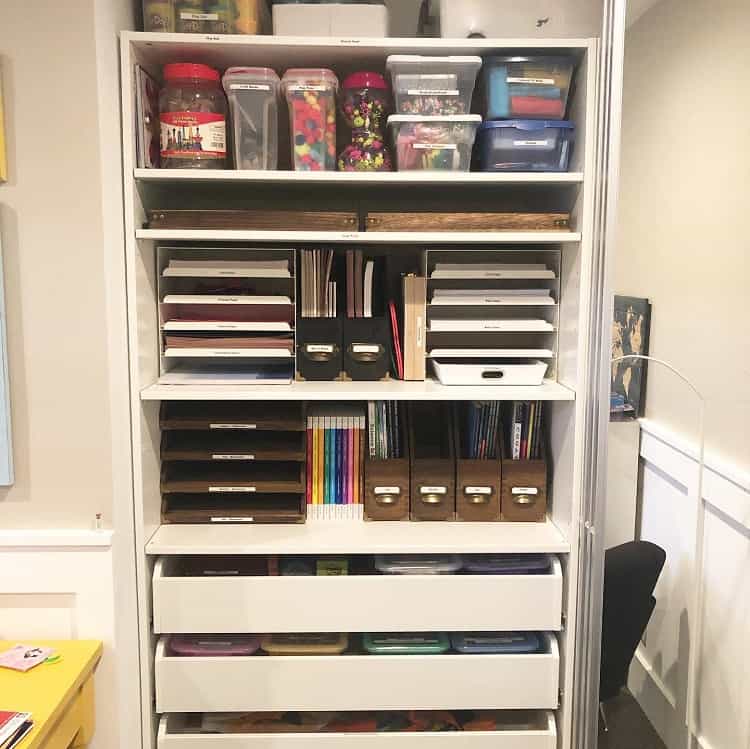 Organized craft supplies in a closet with shelves and labeled containers