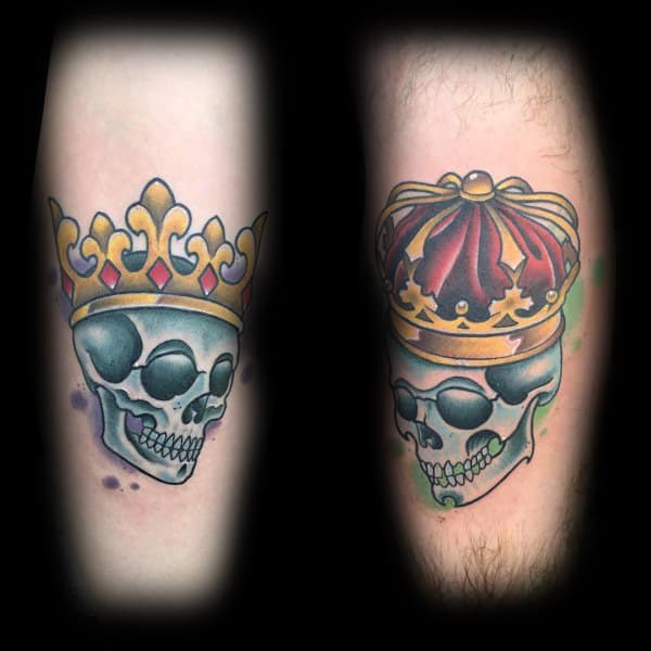 Matching tattoos of crowned skulls in vibrant colors, symbolizing a bold and eternal love between a queen and her king.