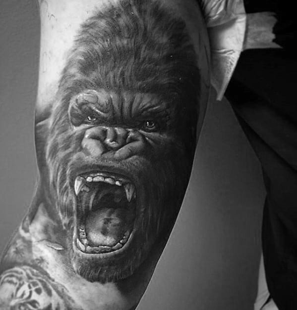 Black and grey King Kong tattoo on arm showing a fierce roaring expression with detailed fur, teeth, and intense eyes.