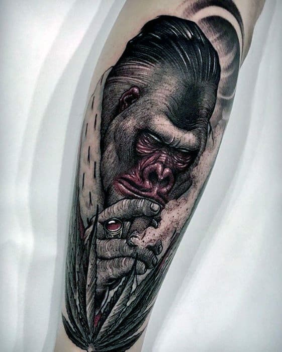 Stylized King Kong tattoo with slicked-back hair, red-toned face, and a suit, holding a joint with a marijuana leaf in the foreground.