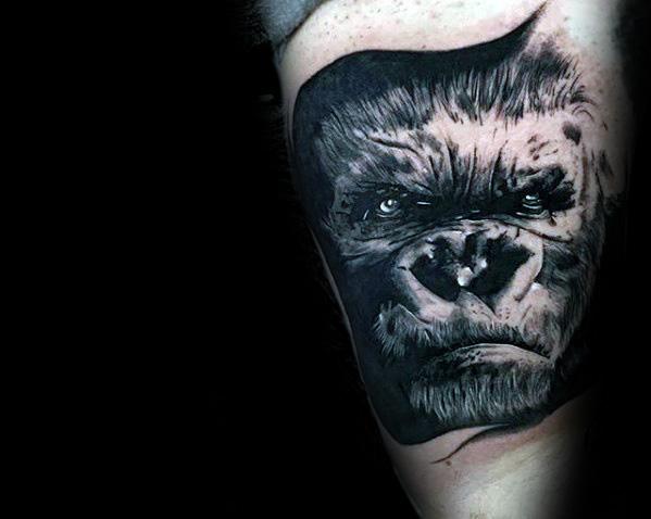 Black and grey King Kong tattoo on upper arm featuring a focused, intense facial expression with high-contrast shading and fine details.