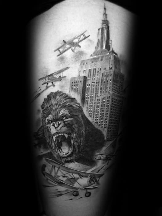 Black and grey King Kong tattoo showing Kong roaring at the base of the Empire State Building with vintage planes flying around.