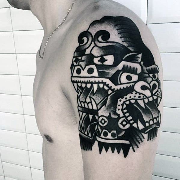 Bold black King Kong tattoo on upper arm in tribal-meets-traditional style, featuring sharp geometric shapes and fierce facial expression.