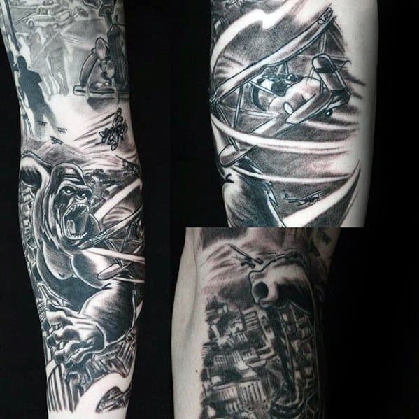 Black and grey King Kong sleeve tattoo showing Kong battling planes mid-air, gripping buildings in a dramatic city destruction scene.