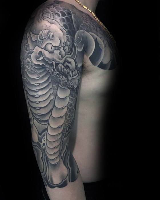 Black and grey Kirin sleeve tattoo with smooth shading, bold scales, and a powerful mythic presence wrapping from shoulder to arm.