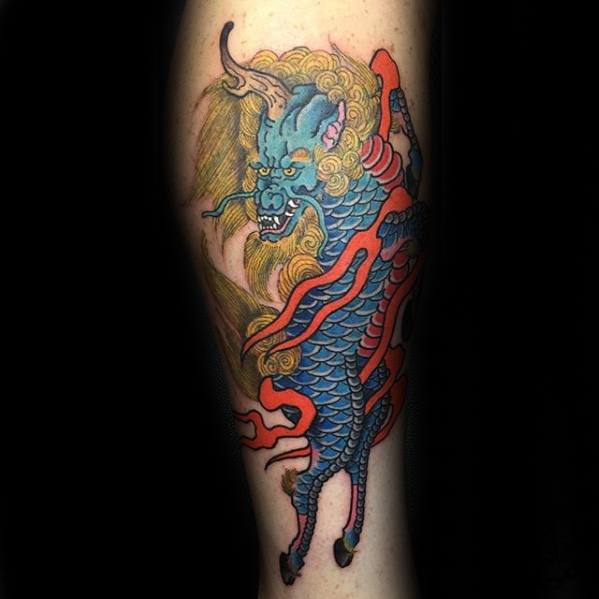 Blue-scaled Kirin tattoo with golden mane and red flames, shown in a dynamic pose with fierce eyes and bold traditional styling.