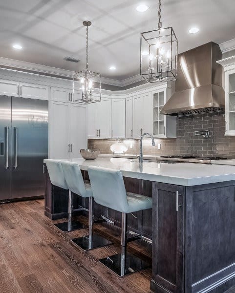 Modern kitchen with white cabinets, gray backsplash, island, and stainless steel appliances.
