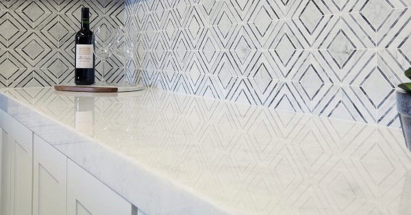 Geometric backsplash design adds a modern, artistic touch to the white countertop.