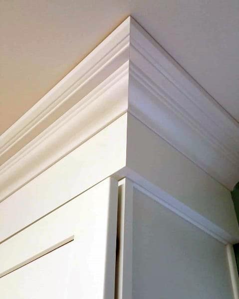 A corner view of kitchen cabinetry with clean, simple white crown molding, adding elegance to the space