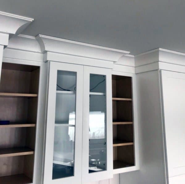 A clean view of kitchen cabinets with elegant white crown molding, showcasing sleek glass doors and a minimalist design