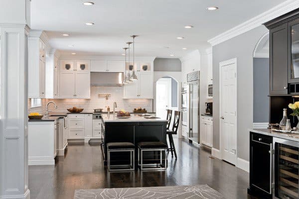 Modern kitchen with white cabinets, a spacious island, dark wood floors, and stainless steel appliances