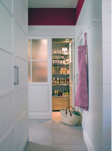 Organized pantry with frosted glass doors, wicker baskets, and neatly stored items.