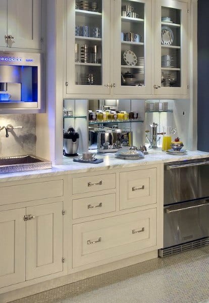 Coffee bar with white cabinets, glass doors, built-in coffee machine, and marble countertop.