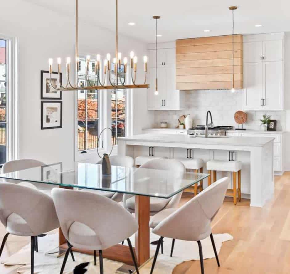 bright open kitchen and dining room white cabinets and island glass table