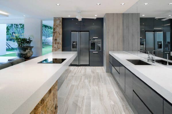 Sleek, modern kitchen with light stone flooring, dark cabinetry, and a minimalist design featuring a spacious countertop and open layout